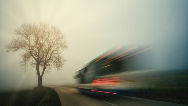 Verschwommen sichtbar ist ein Bus, der an einem Baum vorbeifährt.